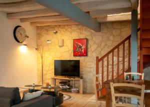 a living room with a tv on a stone wall at Maison de village à Puybrun in Puybrun