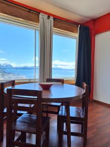 una sala da pranzo con tavolo, sedie e una grande finestra di Aguas Azules a San Carlos de Bariloche
