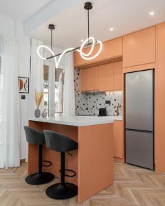 a kitchen with orange cabinets and a kitchen island with bar stools at Oasis Diamond Suite in Thessaloniki