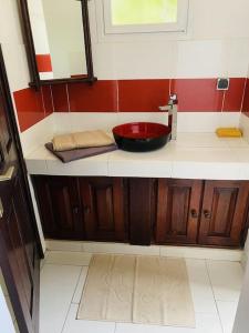 un baño con lavabo y un baño rojo y blanco en La Villa Tila, en Ouoran