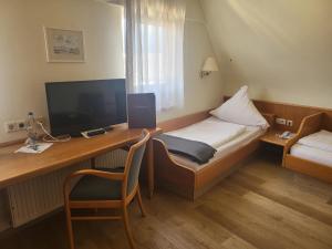 a hotel room with a desk with a bed and a television at Brauereigasthof Dachsenfranz in Zuzenhausen
