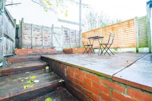 a patio with two chairs and a table on a brick wall at Bright Medway studio flat opposite Chatham station in Chatham