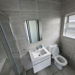 a bathroom with a toilet and a sink and a mirror at Prunell in midrand in Midrand
