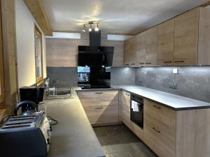 een keuken met houten kasten en een kookplaat met oven bij Chalet haut de gamme 8 chambres avec sauna à 250m des pistes, St Martin de Belleville - FR-1-452-75 in Saint-Martin-de-Belleville