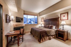 a bedroom with a bed and a desk and a window at Silverado Lodge by All Seasons Resort Lodging in Park City
