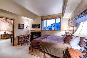 a bedroom with a bed and a desk and a fireplace at Silverado Lodge by All Seasons Resort Lodging in Park City