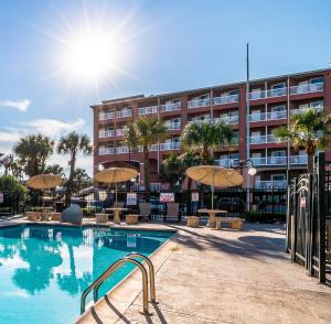 a swimming pool with chairs and umbrellas in front of a building at Quality Inn & Suites Galveston - Beachfront in Galveston