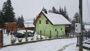 una casa verde con una valla en la nieve en Vikendica Gojković, en Skender Vakuf