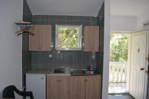 een keuken met houten kasten, een wastafel en een raam bij Apartment Vidakovic in Budva