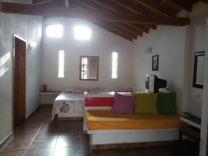 a room with a bed with colorful pillows on it at Villa Cocuyo - Studios & Apartments in El Cardón +28 photos