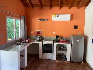 a kitchen with orange walls and a stove and a sink at Villa Cocuyo - Studios & Apartments in El Cardón