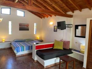 a bedroom with a bed and a chair and a tv at Villa Cocuyo - Studios & Apartments in El Cardón
