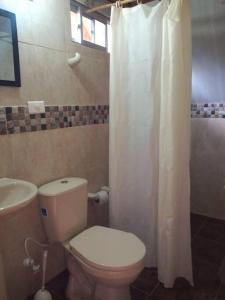 a bathroom with a toilet and a white shower curtain at Hermosa cabaña con huerta - Casa verde in Medellín