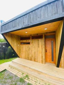 une maison en bois avec une terrasse en bois dans la cour dans l'établissement Forest house Cabaña para 2, à Pichilemu