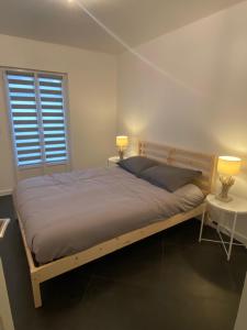 a bedroom with a bed with two lamps and a table at Maison cosy in Courrejean