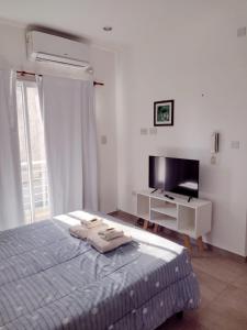 ein weißes Schlafzimmer mit einem Bett und einem TV in der Unterkunft DTo CÉNTRICO LOBOS 1 C in Lobos
