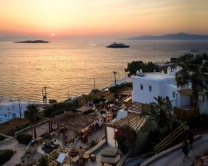 un tramonto sull'oceano con una nave da crociera in lontananza di Legacy Suites a Mykonos Città