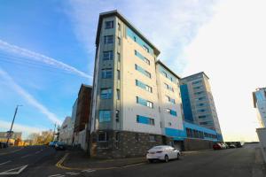 un coche blanco estacionado frente a un edificio alto en Glas-Go 2 bedroom Apartment 3 min walk to SECC Hydro FREE PARKING ONSITE, en Glasgow