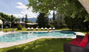 einen Pool in einem Garten mit Stühlen und einer Frau in der Unterkunft Hotel ANDER in Bruneck