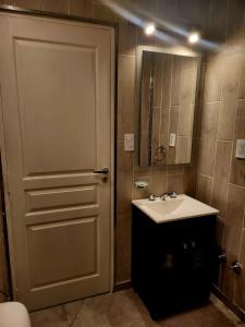 ein Bad mit einer Tür, einem Waschbecken und einem Spiegel in der Unterkunft F&E Apartment in Necochea
