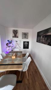 uma sala de jantar com uma mesa de vidro e cadeiras brancas em Cosy Apartment à 20 min de Paris em Fresnes