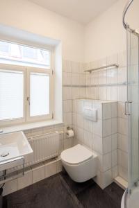 a white bathroom with a toilet and a sink at Hotel Schwanen in Memmingen