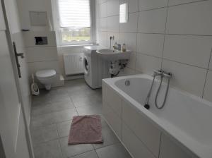 y baño con bañera, lavabo y aseo. en Furnished apartments for employees with separate rooms, en Zeitz