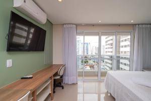 1 dormitorio con cama, escritorio y ventana en Flat no melhor do Bueno, en Goiânia