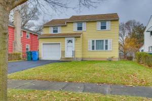 a yellow house with a garage in a yard at Convenient, Pet-Friendly Rochester Vacation Rental in Rochester