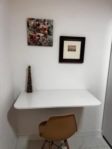 a white desk with a chair and two pictures on the wall at Lindo apartamento com vista mar - Aquarius Residence in Fortaleza