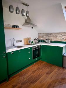 a green kitchen with a sink and a stove at Bill's Barns Apartment 2 in Kenmare