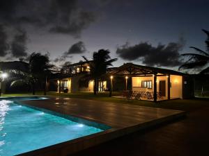 una casa con piscina por la noche en Pousada Villa Sagi, en Baía Formosa