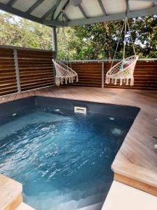 una piscina con due sedie e un'altalena di Cottages Les Ventilés a Deshaies
