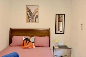 Un dormitorio con una cama con sábanas rosas y una mesa. en Casa Matatiso - quartos privados em casa compartilhada, en Abraão