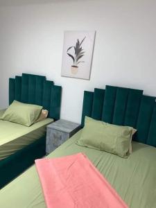 um quarto com duas camas e uma cabeceira verde em شقه سكنيه مفروشه بكورنيش المعادي no Cairo