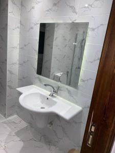 uma casa de banho branca com um lavatório e um espelho em شقه سكنيه مفروشه بكورنيش المعادي no Cairo