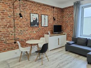 un soggiorno con muro di mattoni, tavolo e sedie di Konopnickiej 9 Apartament Loft dostęp na kod a Pabianice