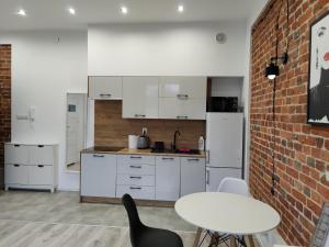 a kitchen with white cabinets and a brick wall at Konopnickiej 9 Apartament Loft dostęp na kod, Ptak, Orientarium, Atlas ARENA, Szpital, Mandoria, Fala, Centrum Zdrowia Matki Polki, Rodzina, Family, bezpłatny parking in Pabianice