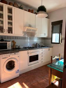 een keuken met een fornuis, een wasmachine en een droger bij Aura rural II in San Pablo de los Montes
