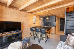 a kitchen with a bar with stools and a television at Val Thorens - Cosy Duplex avec Vue Pied des pistes Silveralp 570 in Val Thorens