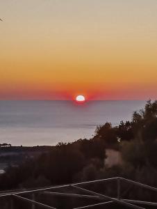 um pôr-do-sol sobre o oceano com o sol no céu em Irida's house em Cefalônia