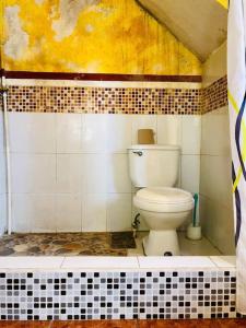 a bathroom with a toilet in a tiled room at Mi casa es tu casa in San Pedro La Laguna