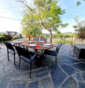 einen Holztisch und Stühle auf einer Steinterrasse in der Unterkunft Le Casimir, Maison de campagne à Estaing in Le Nayrac