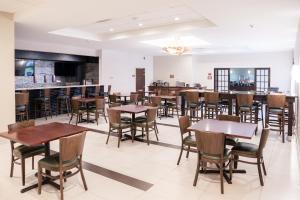 Best Western Plus Philadelphia Bensalem Hotel في بنسالم: غرفة طعام مع طاولات وكراسي وبار