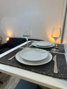 - une table avec 2 assiettes blanches et 2 verres à vin dans l'établissement Studio Cosy proche Paris, à Clichy