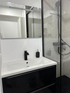 uma casa de banho com um lavatório branco e um chuveiro em Studio Cosy proche Paris - JO 2024 em Clichy