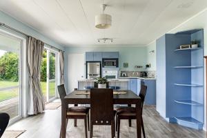 a kitchen and dining room with a table and chairs at Calypso Cottage in Raglan