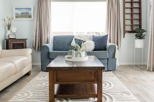 a living room with a blue couch and a coffee table at Calypso Cottage, Bright bach, Water view in Raglan