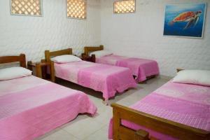 3 posti letto in una camera con lenzuola rosa di Hotel Rancherío Shangai a Moñitos