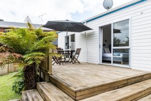 a patio with an umbrella and a table and chairs at Calypso Cottage in Raglan